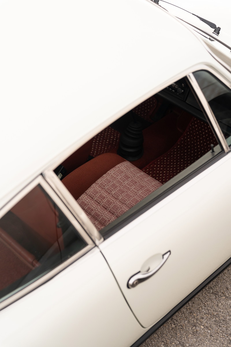 1974 Porsche 911 coupe interior with plaid fabric seats and black shift knob.