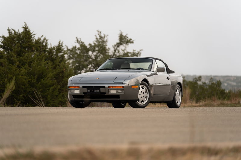 Front 3/4 view of a grey 1990 Porsche 944 S2 Cabriolet with factory rims.