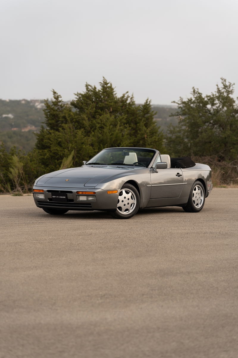 A 1990 Porsche 944 S2 Cabriolet in Titanium Metallic, with cup-style rims.