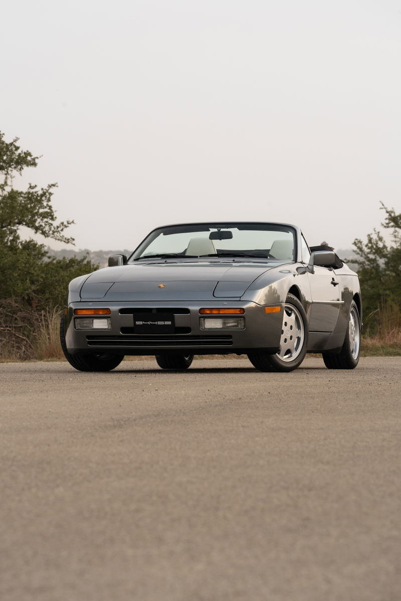 A grey 1990 Porsche 944 S2 Cabriolet convertible with silver alloy rims and black trim.