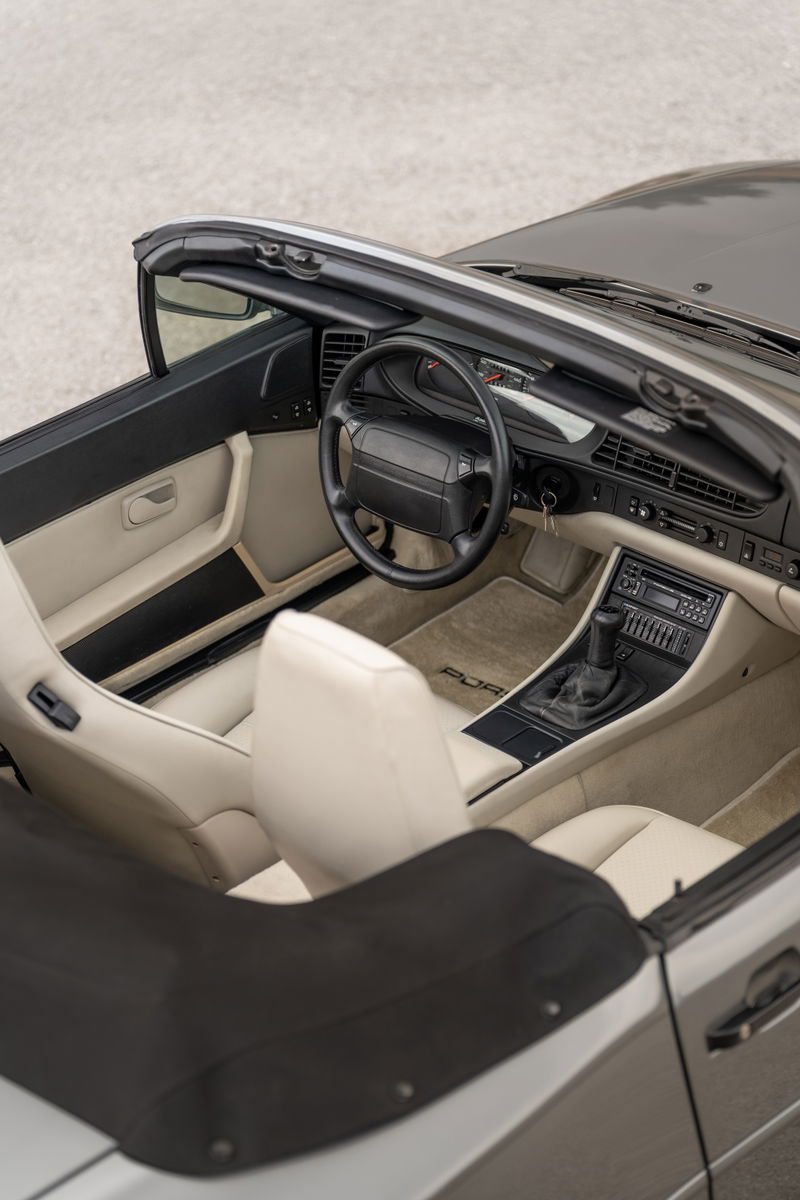 Interior view of a 1990 Porsche 944 S2 Cabriolet in Titanium Metallic, featuring cream leather seats and dashboard trim.