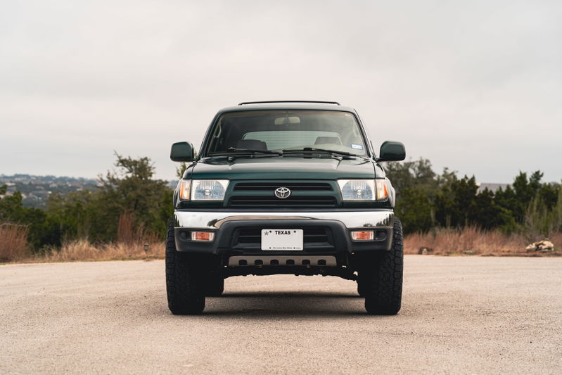 Front view of a dark green 2000 Toyota 4Runner with chrome trim and black rims.