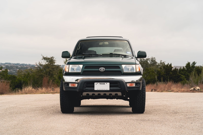 Front view of a dark green 2000 Toyota 4Runner with chrome trim and black rims.