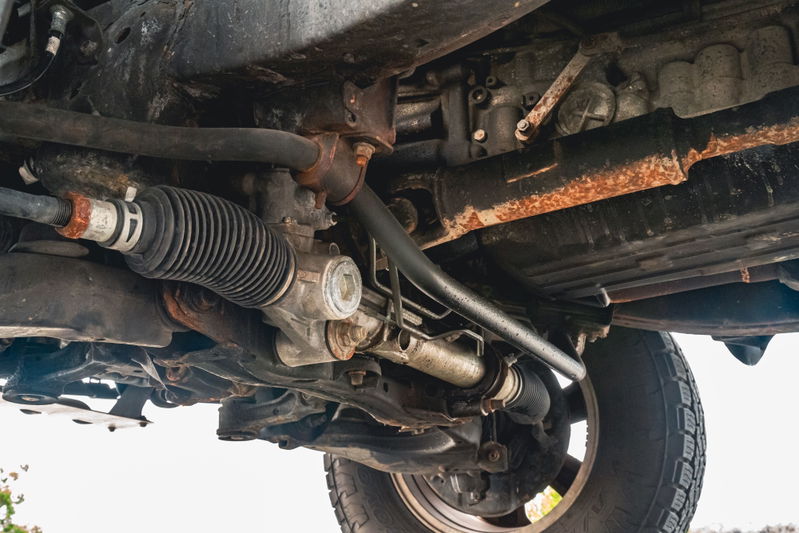 Underneath view of a 2000 Toyota 4Runner showing the steering rack, sway bar, and tire.