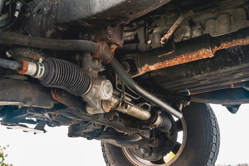 Underneath view of a 2000 Toyota 4Runner showing the steering rack, sway bar, and tire.
