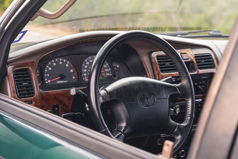 Interior dashboard and steering wheel of a 2000 Toyota 4Runner with faux wood trim.