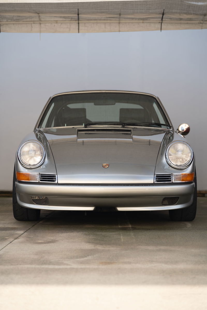 Silver Porsche 911 with chrome trim and round headlights.