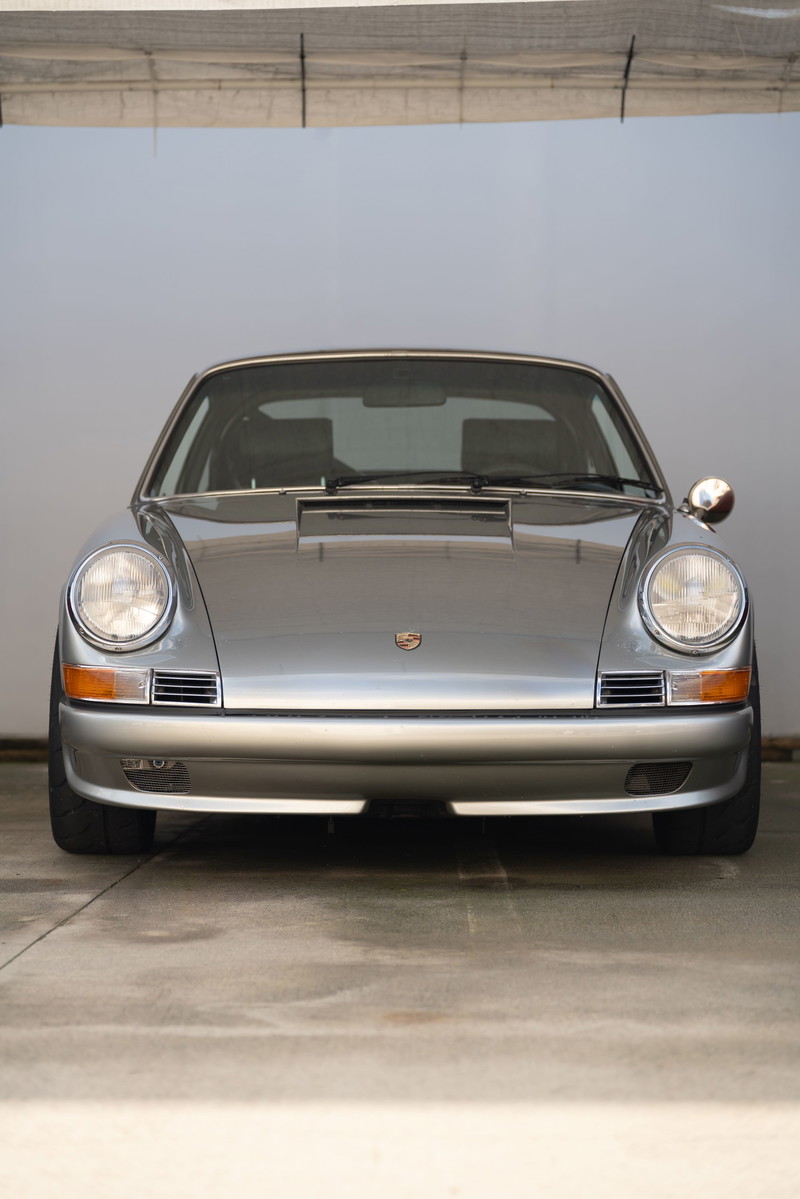 Silver Porsche 911 with chrome trim and round headlights.