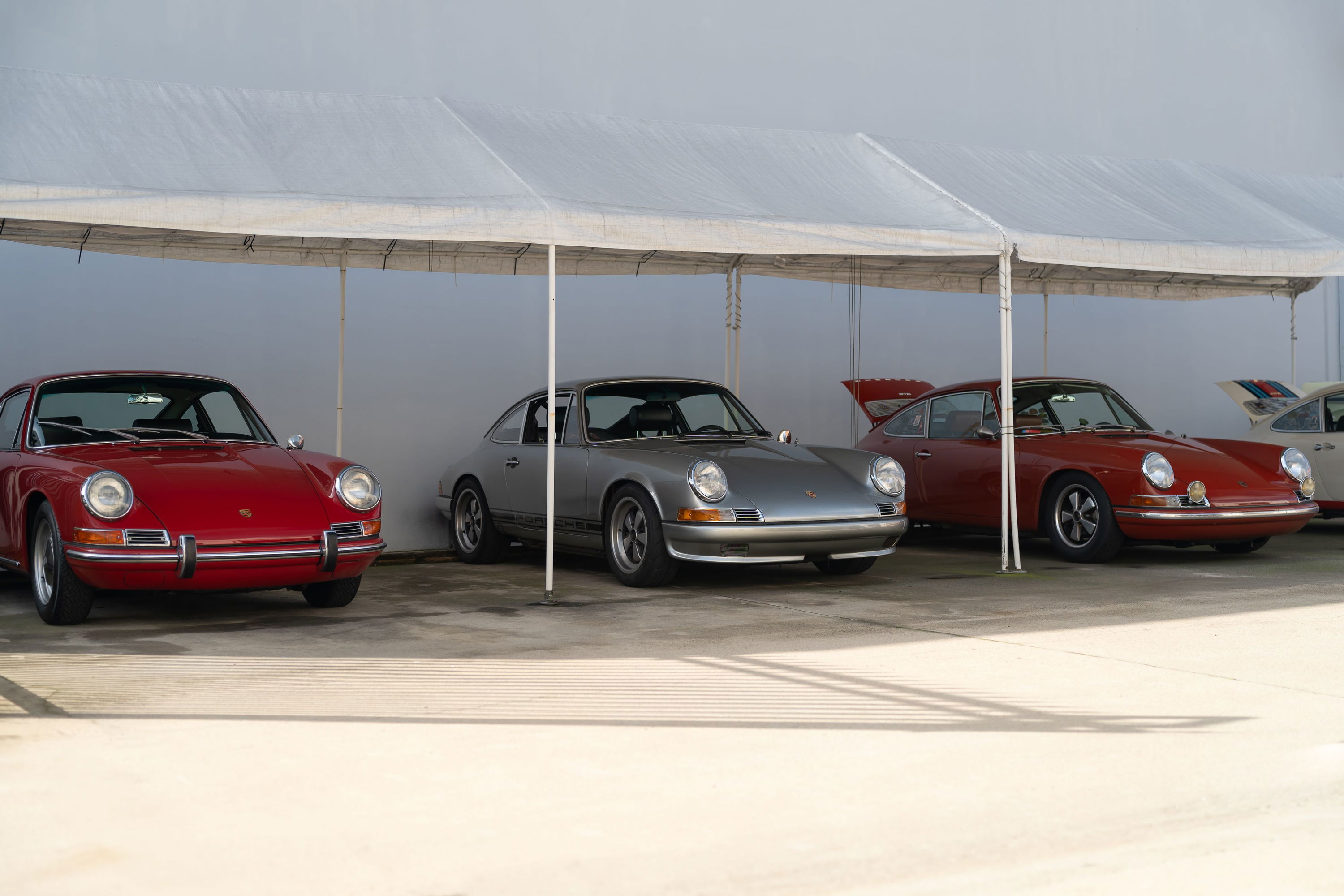 Red Porsche 911 coupe parked under a white tent at the Lit Show LA.