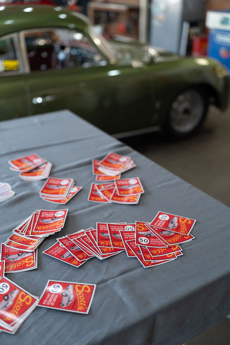 Green Porsche 356 with red "Scotts 50 Years" stickers and a polished rim.