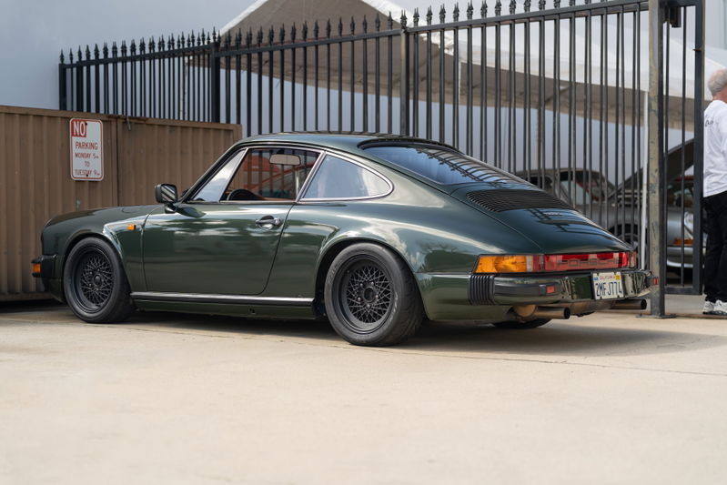 Dark green 1974-1989 Porsche 911 Carrera with black mesh rims.