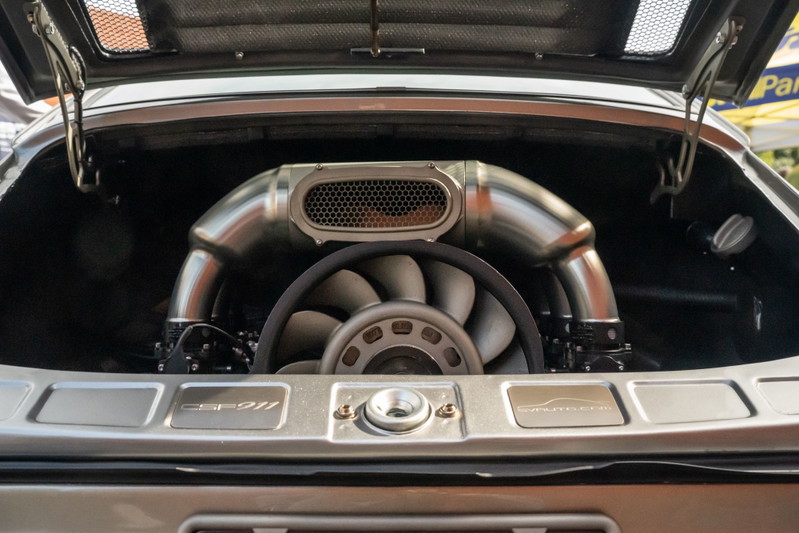 Silver Porsche 911 engine bay with custom exhaust and fan.