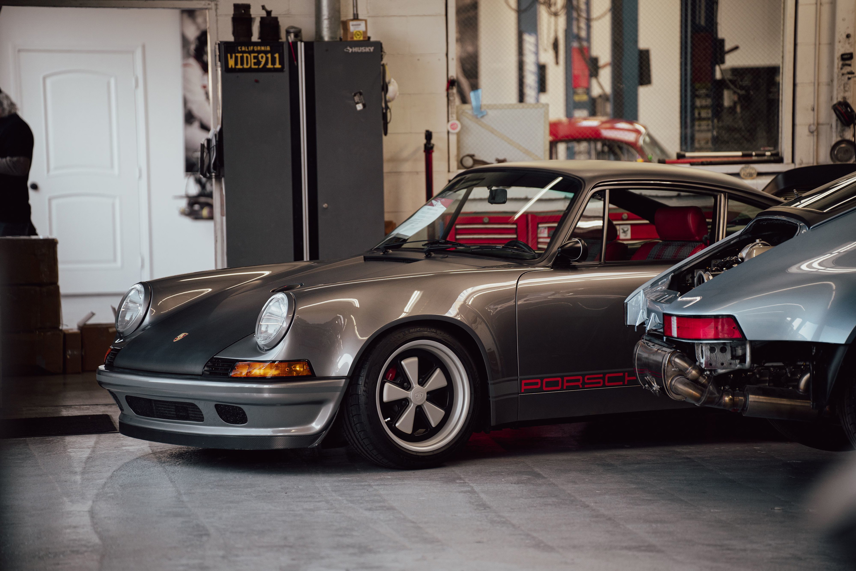 Grey Porsche 911 with red "PORSCHE" livery and Fuchs rims.