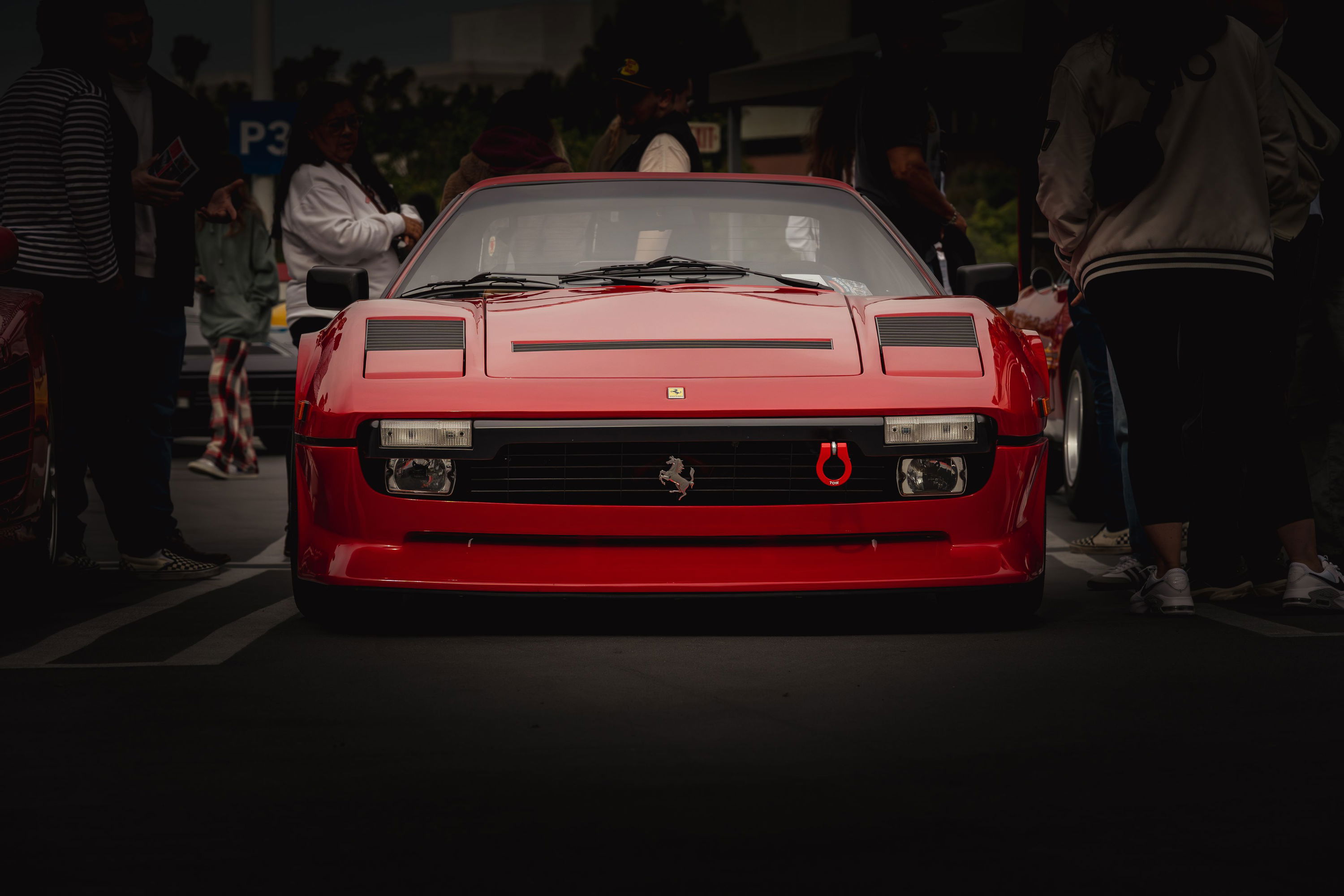Low-angle front view of a red Ferrari Testarossa with aftermarket red tow hook.