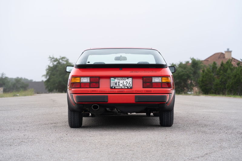 Red 1981 Porsche 924 Turbo from behind, with a spoiler and stock trim.
