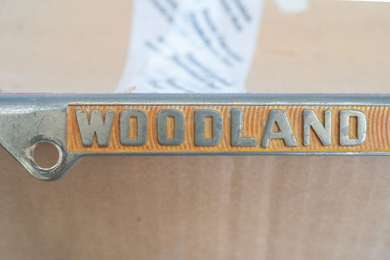 "Woodland" badge on a gold-plated Competition Motors vehicle frame.