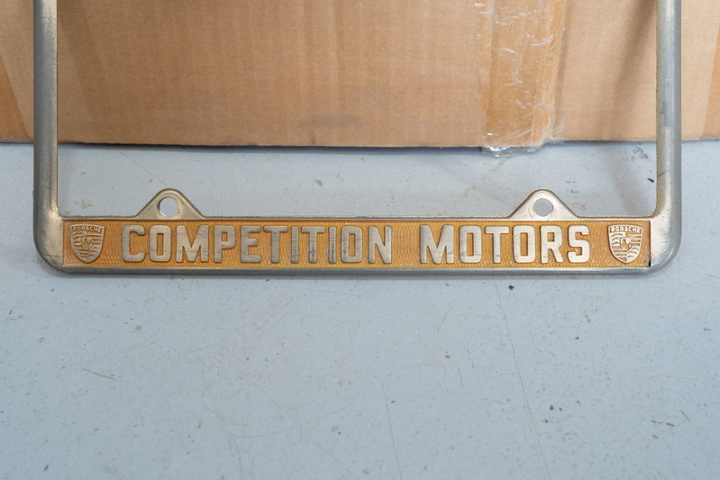 Vintage Porsche Competition Motors license plate frame with gold enamel trim.