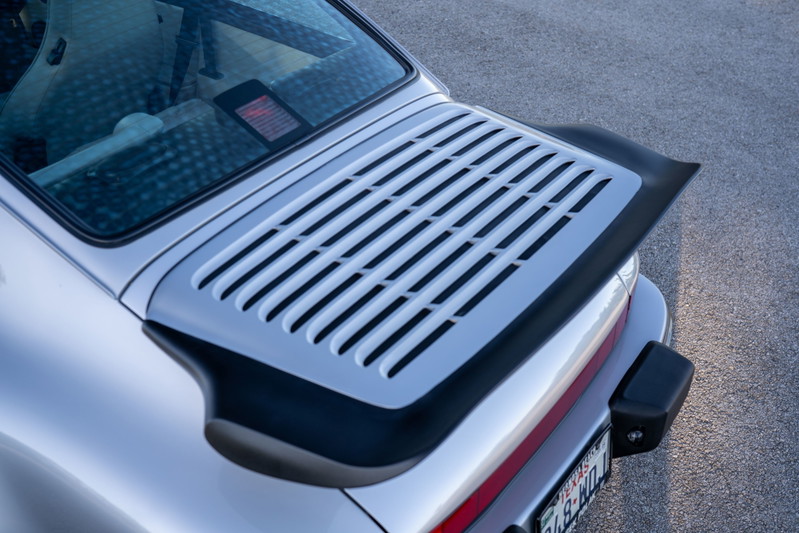 Close-up of the silver 1987 Porsche 911 Carrera's rear decklid and spoiler.