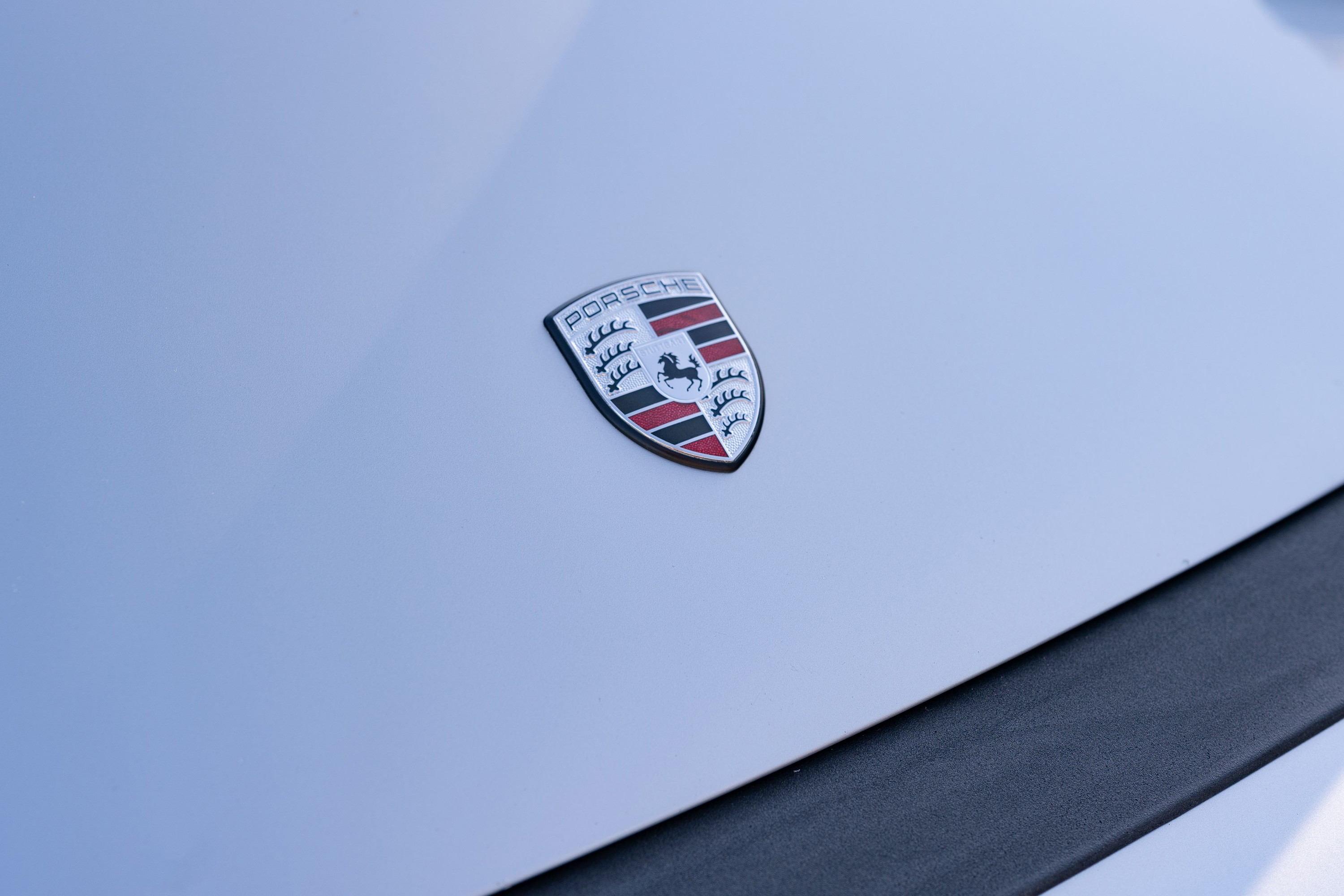 Close-up of a silver metallic 1987 Porsche 911 Carrera's hood emblem.