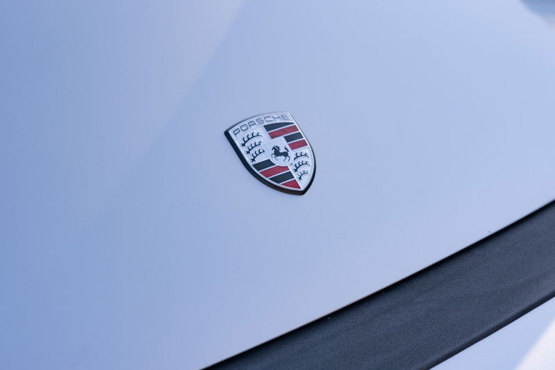 Close-up of a silver metallic 1987 Porsche 911 Carrera's hood emblem.