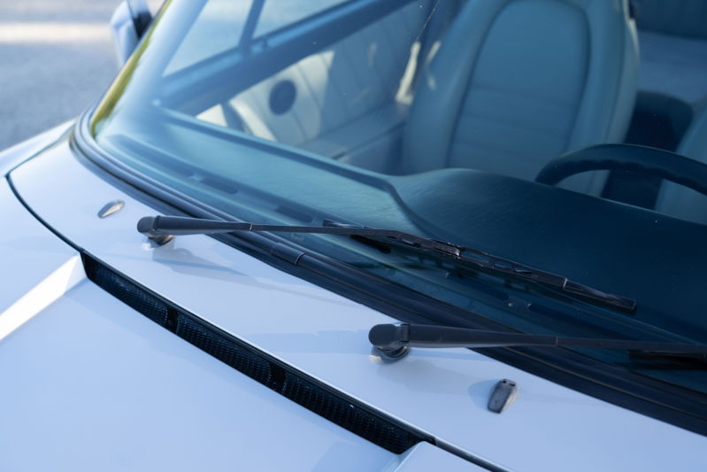Close-up of silver metallic 1987 Porsche 911 Carrera G50 windshield wipers.