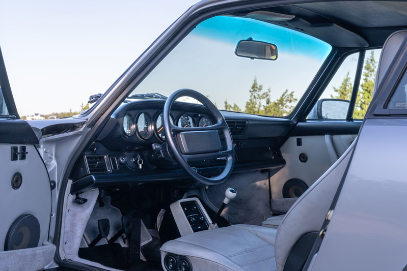 Interior of a silver 1987 Porsche 911 Carrera G50, showing the dashboard, steering wheel, and seats.