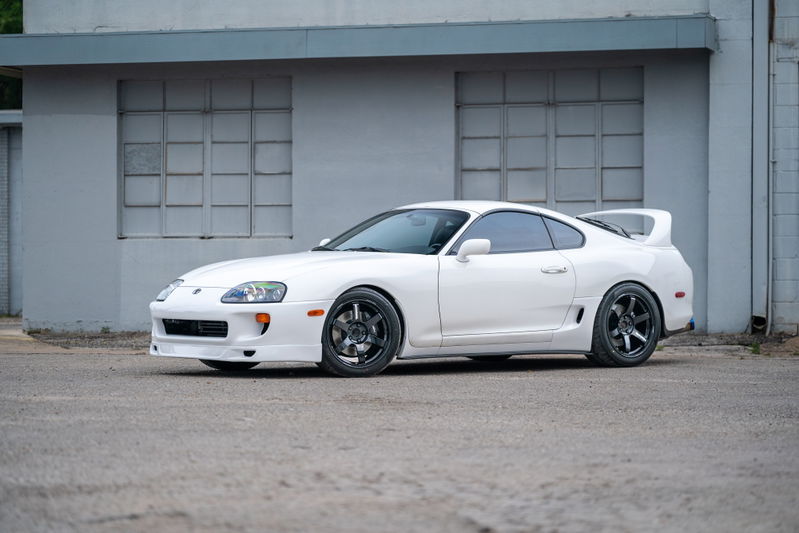 White 1994 Toyota Supra with aggressive body kit and aftermarket black rims.