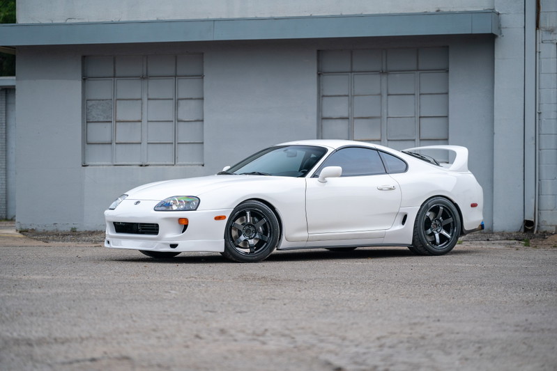 White 1994 Toyota Supra with aggressive body kit and aftermarket black rims.