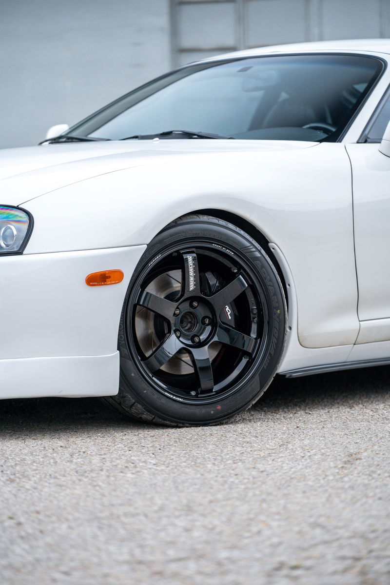White 1994 Toyota Supra with black 5-spoke TE37 rims and low profile tires.