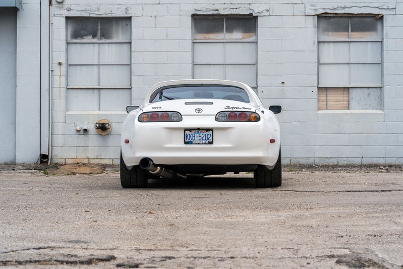 White 1994 Toyota Supra Targa, modified with an aftermarket exhaust and wide rear tires.