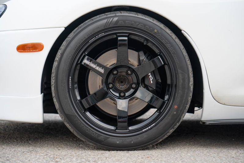 Close-up of a white 1994 Toyota Supra's black 6-spoke TE37 rims and Yokohama Advan tires.