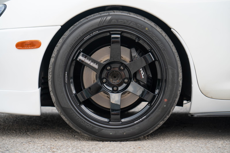 Close-up of a white 1994 Toyota Supra's black 6-spoke TE37 rims and Yokohama Advan tires.