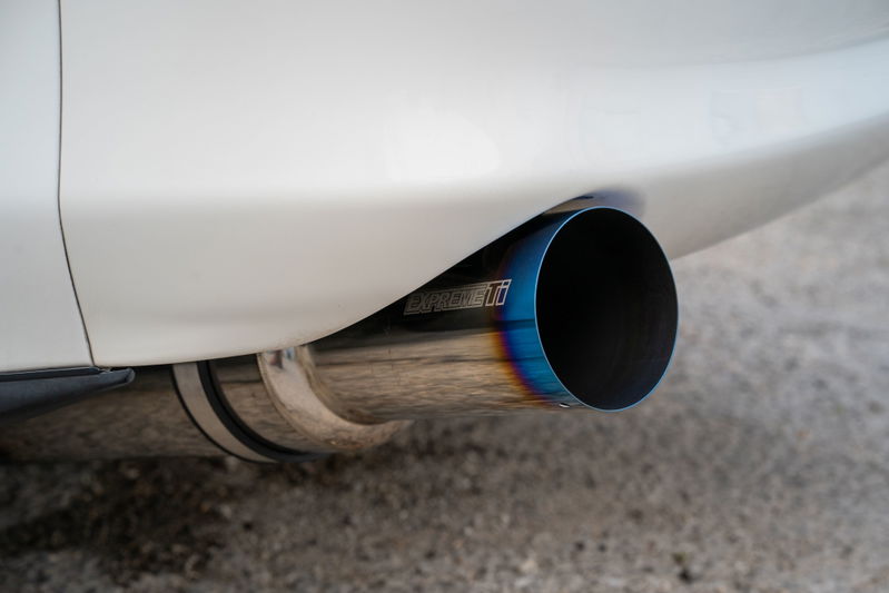 Close-up of a white 1994 Toyota Supra's burnt titanium exhaust tip.