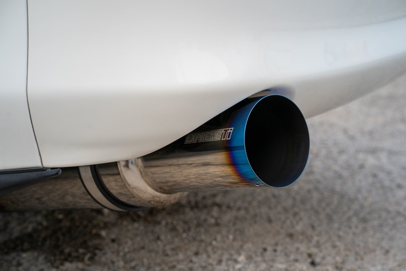 Close-up of a white 1994 Toyota Supra's burnt titanium exhaust tip.