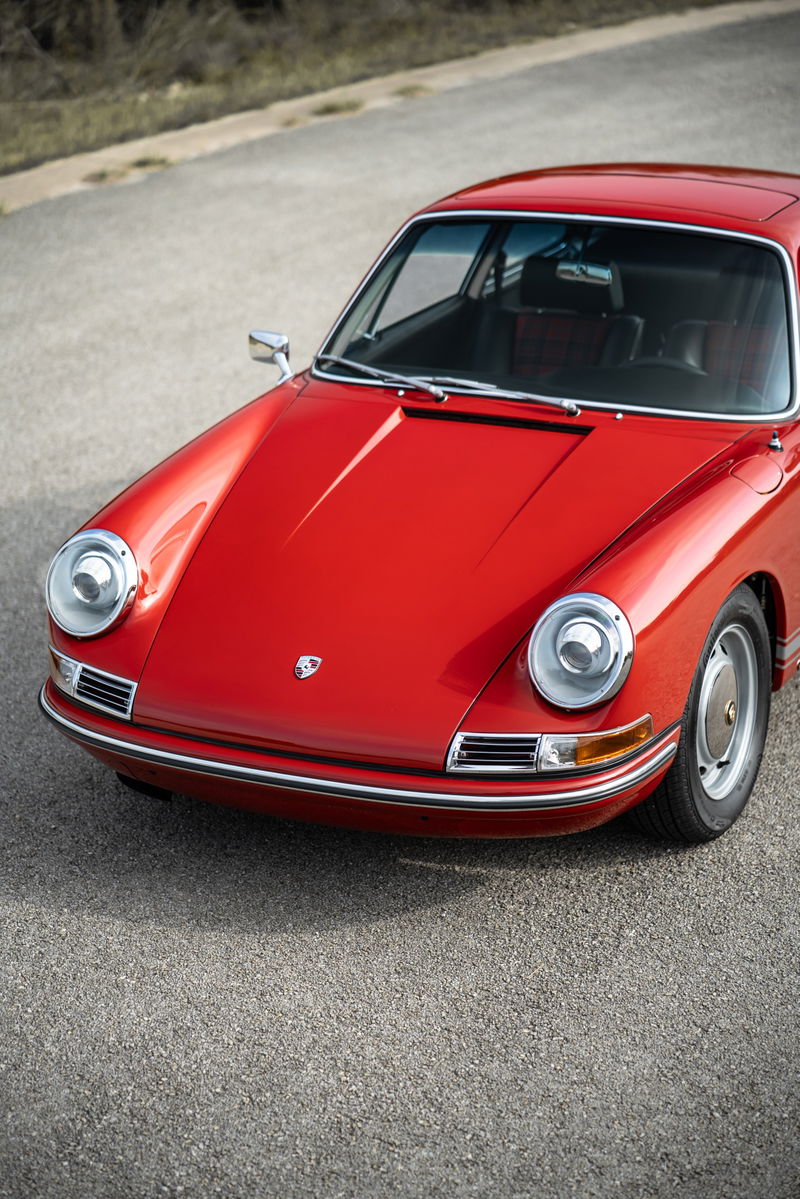 Front view of a red 1967 Porsche 912 Coupe with chrome trim and original rims.