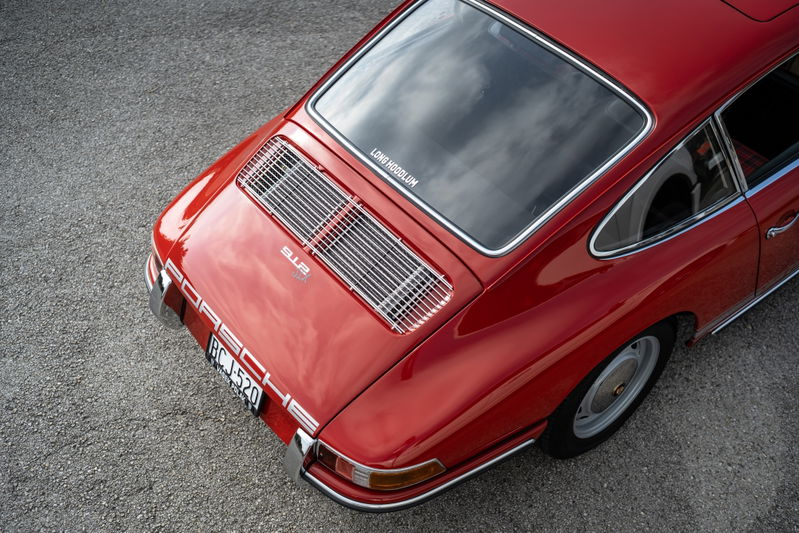 Rear view of a red 1967 Porsche 912 coupe with chrome trim and a rear engine grille.