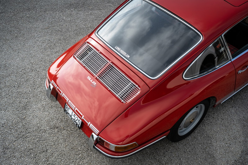 Rear view of a red 1967 Porsche 912 coupe with chrome trim and a rear engine grille.