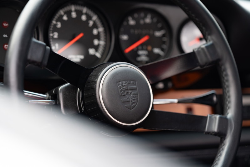 Classic Porsche 912 steering wheel with crest and analog gauges.