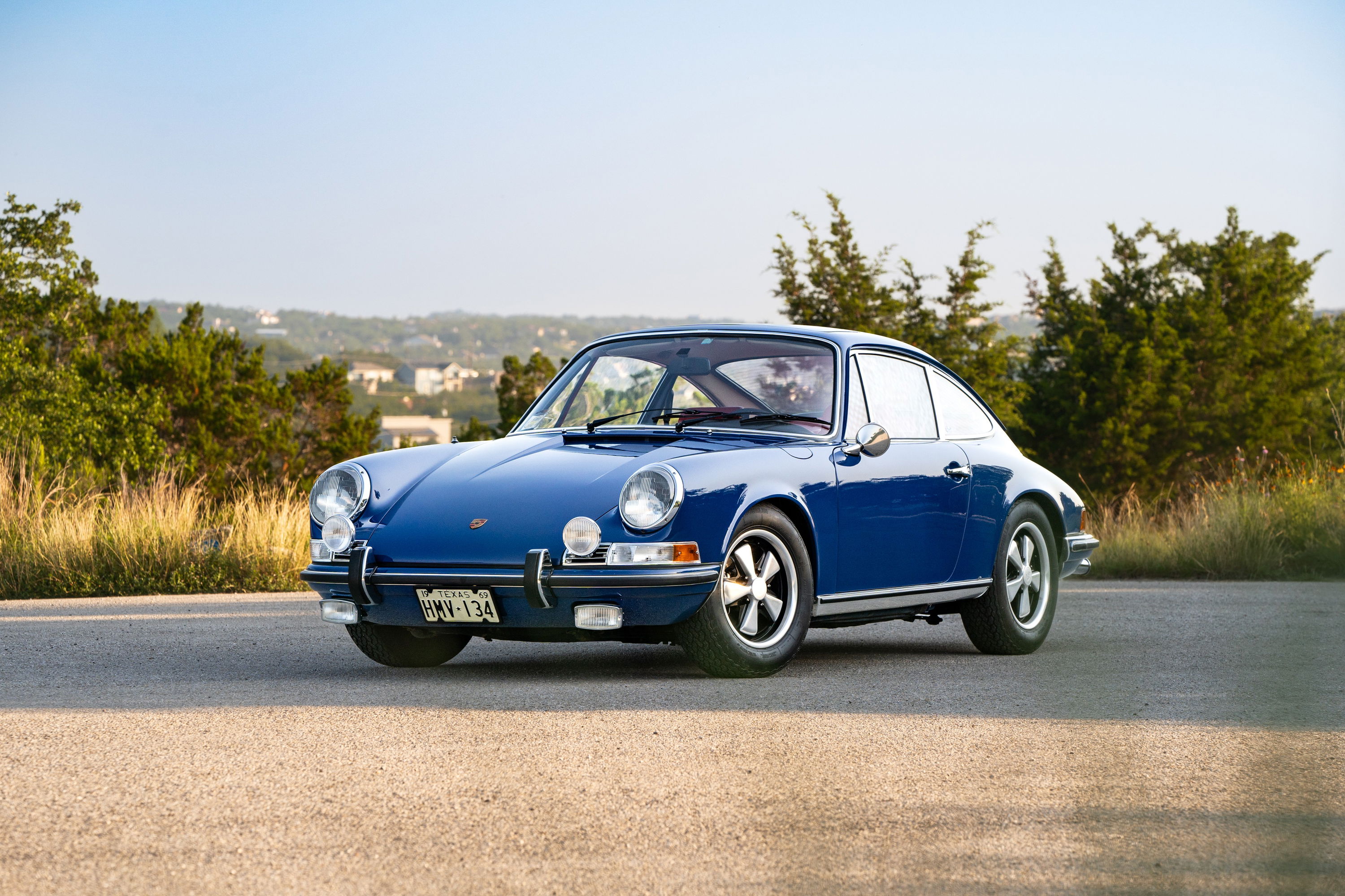 A blue 1969 Porsche 911S coupe with chrome trim and Fuchs wheels.