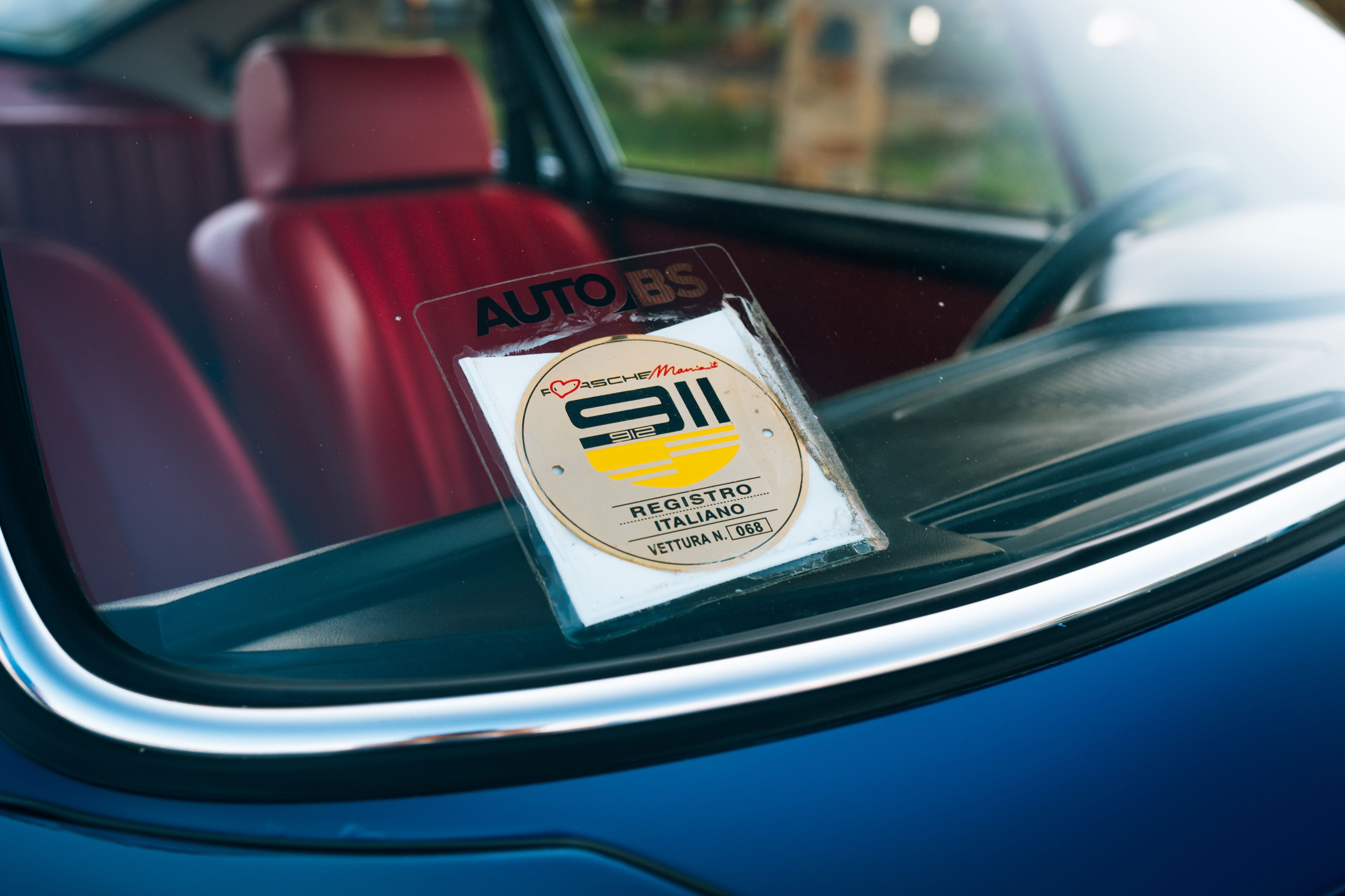 Blue 1969 Porsche 911S interior with red seats and an "Auto BS" sticker on the windshield.