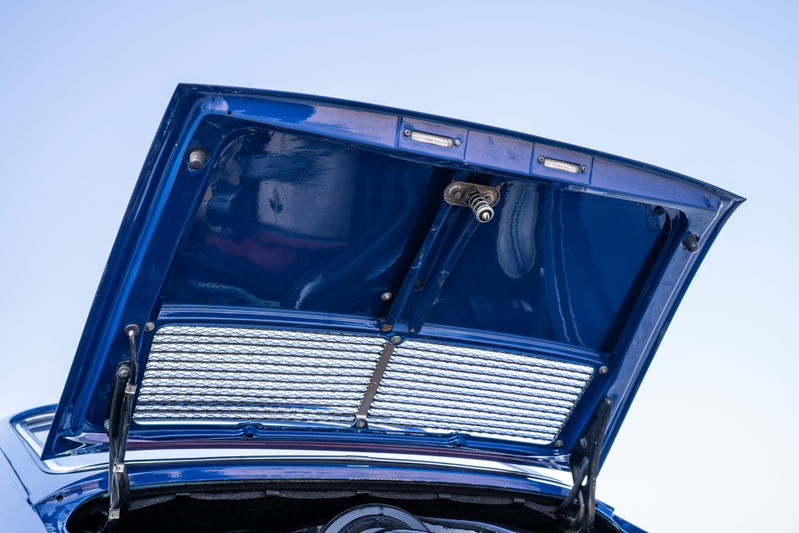 Open hood of a blue 1969 Porsche 911S shows a satin grille and interior detail.