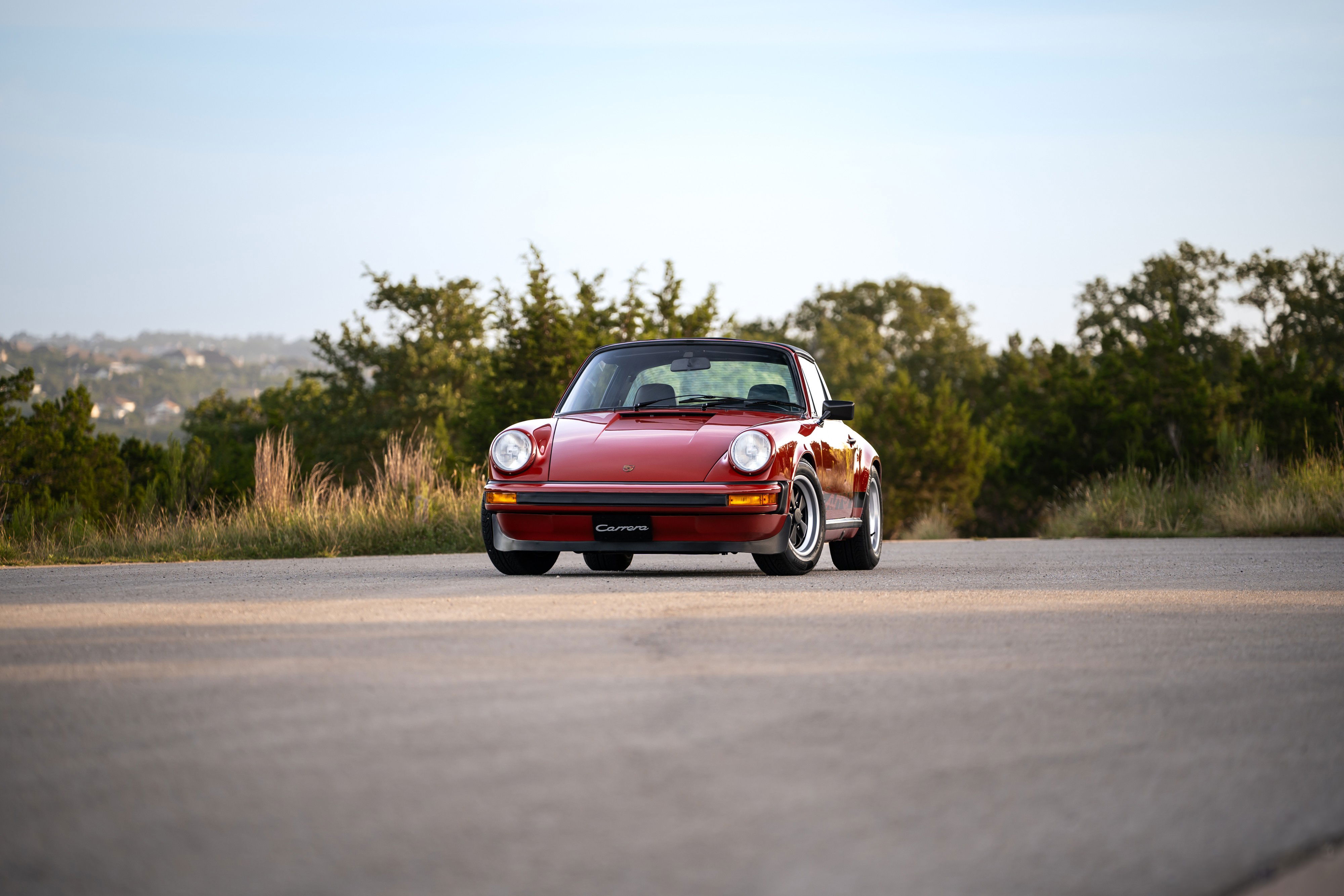 Red 1974 Porsche 911 Carrera Targa with black targa top and Fuchs rims.