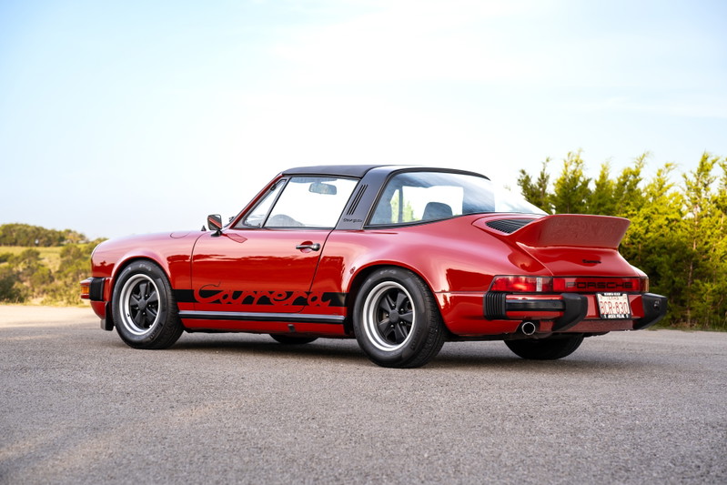 Red 1974 Porsche 911 Carrera Targa with black trim, gold lettering, and Fuchs rims.