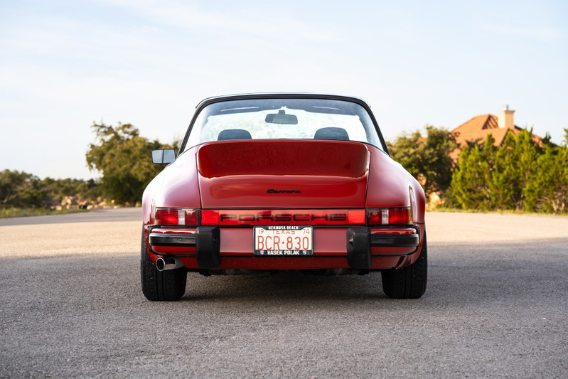 Rear view of a red 1974 Porsche 911 Carrera Targa, showing off its classic taillights and bumper trim.