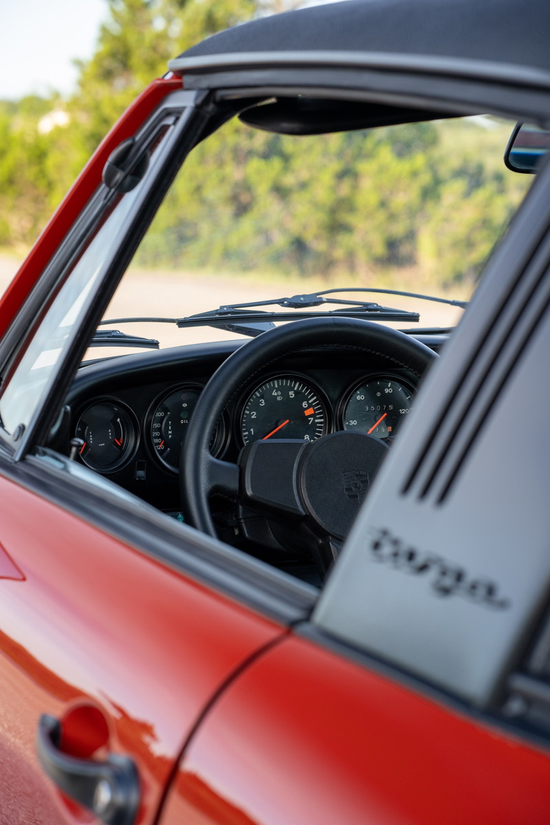 Red 1974 Porsche 911 Carrera Targa interior with classic gauges and "Targa" badging.
