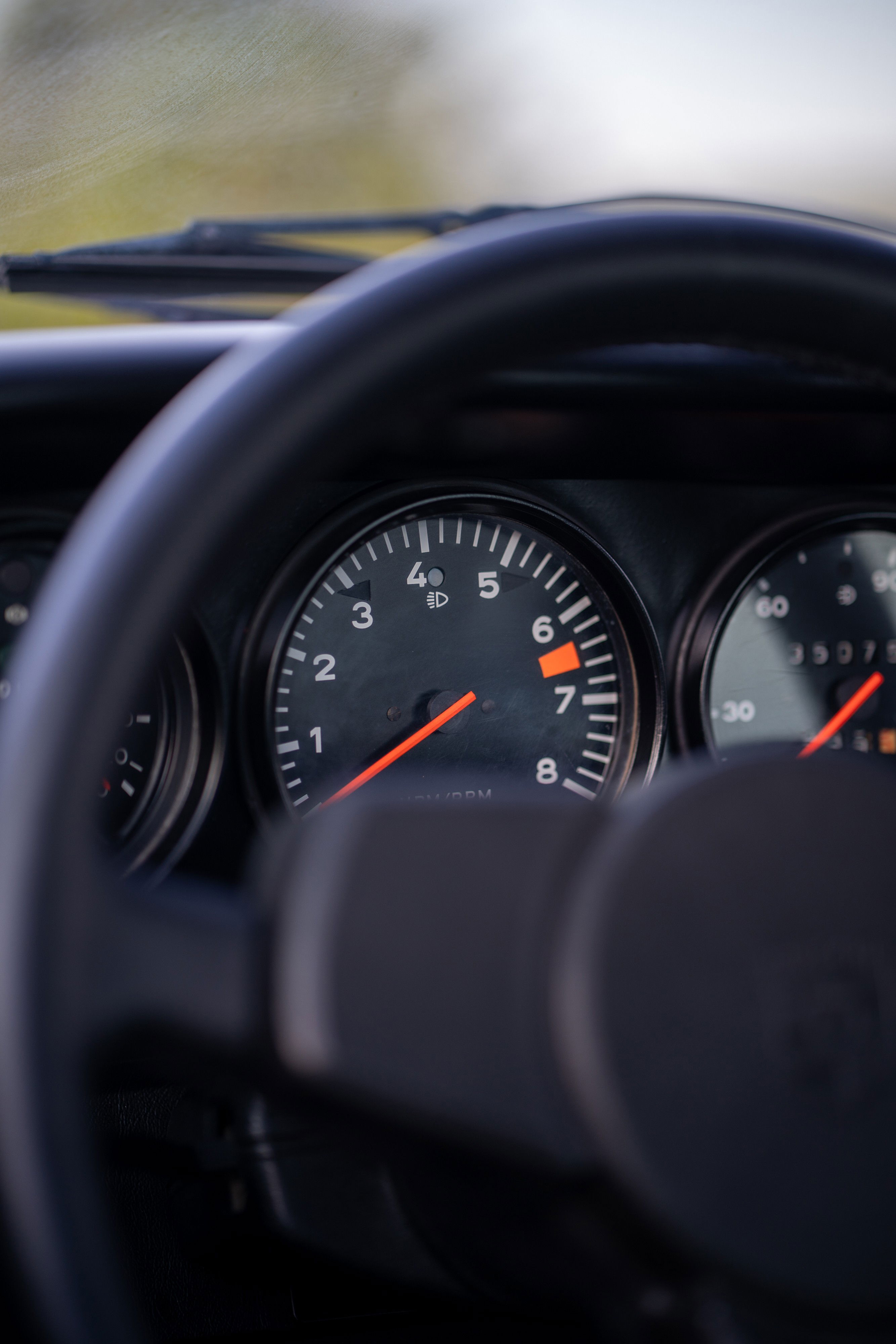 Close up of a red 1974 Porsche 911 Carrera Targa dashboard with tachometer.