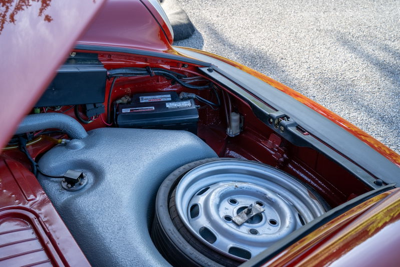 Red 1974 Porsche 911 Carrera Targa spare tire well with battery and fuel tank.
