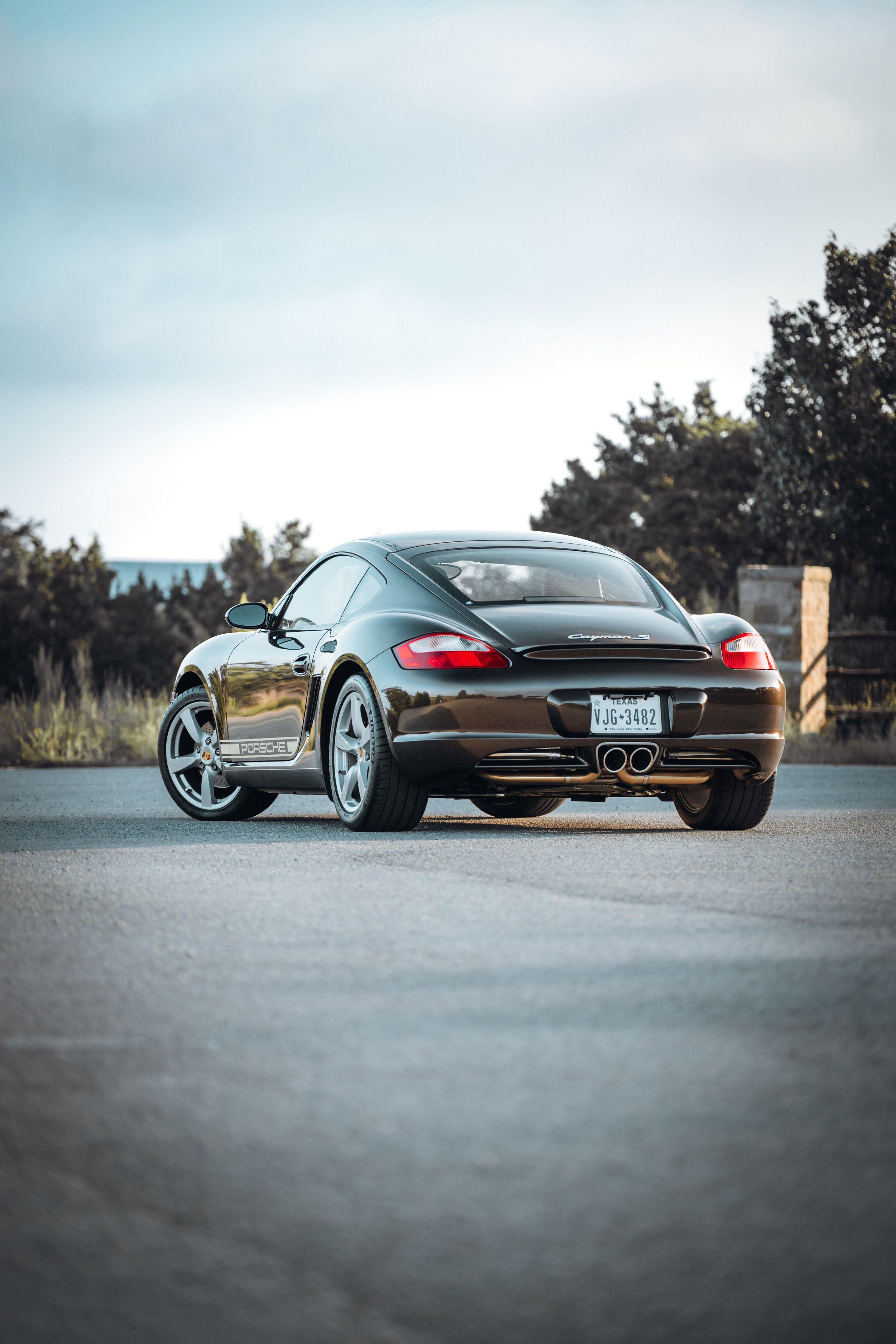 Rear view of a Macadamia Metallic 2008 Porsche Cayman S coupe with silver multi-spoke rims and dual exhaust tips.