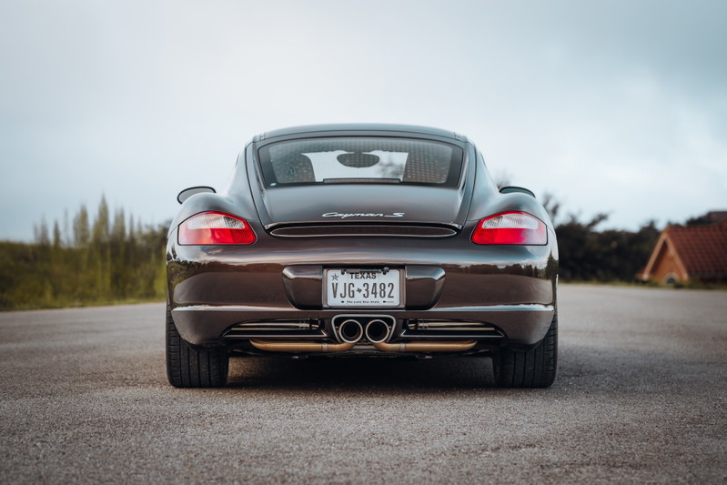 Rear view of a Macadamia Metallic 2008 Porsche Cayman S with quad exhaust tips.