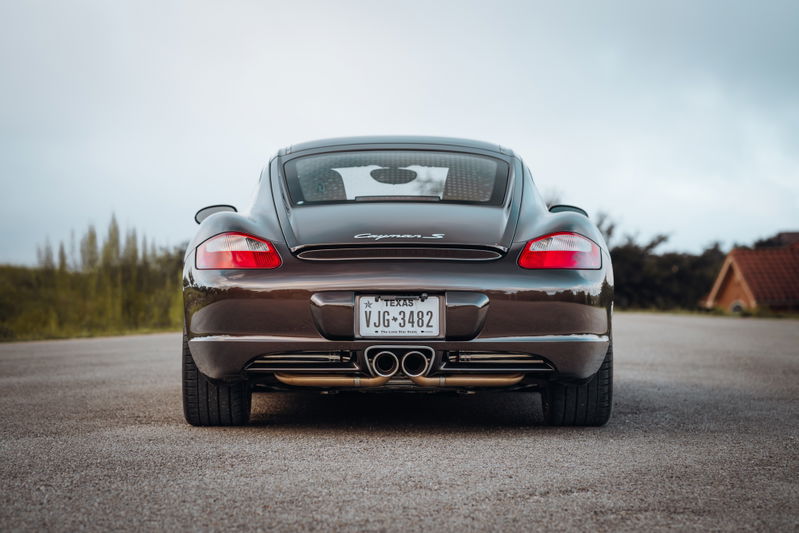 Rear view of a Macadamia Metallic 2008 Porsche Cayman S with quad exhaust tips.